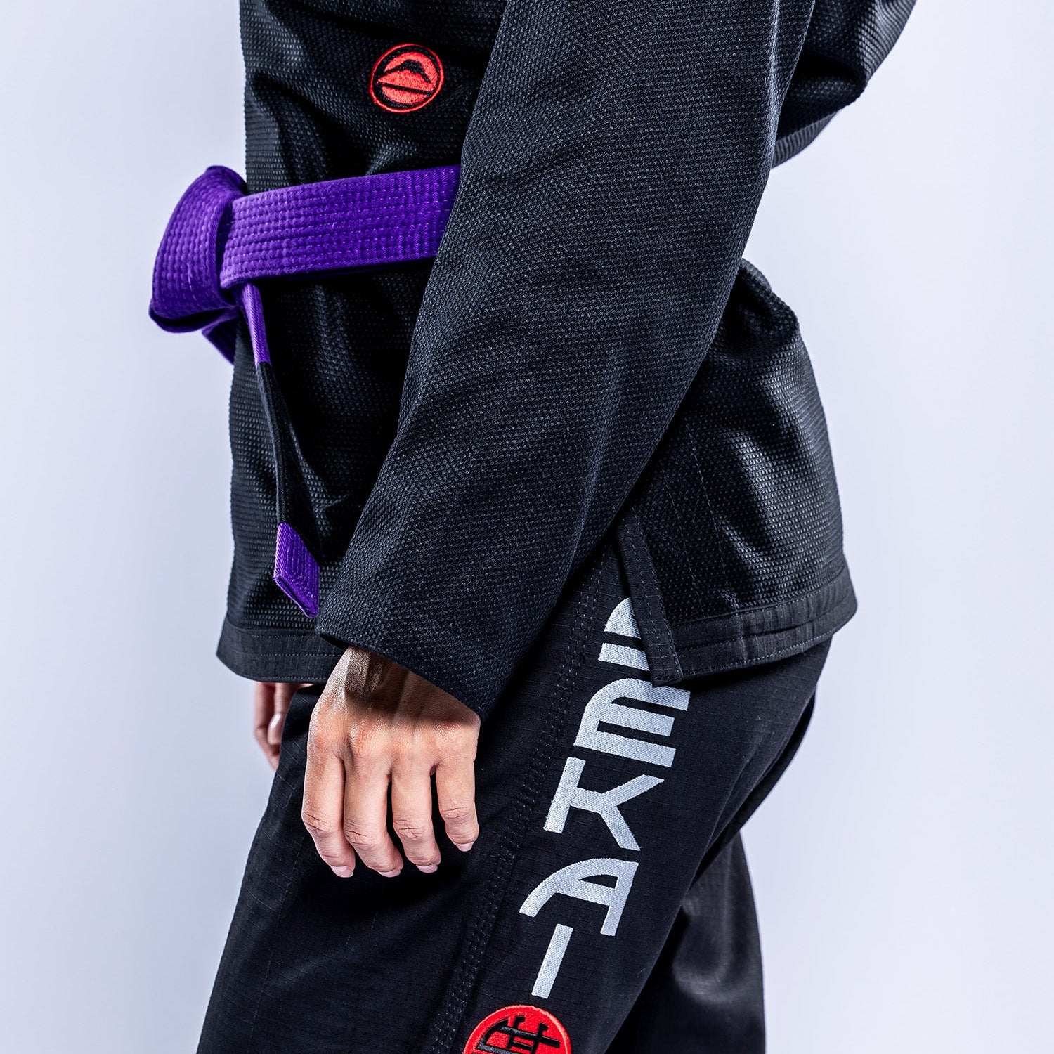 A person wears the Womens SEKAI 3.0 BJJ Gi Black Grey, standing against a plain background with their left arm, torso, and leg partially visible.