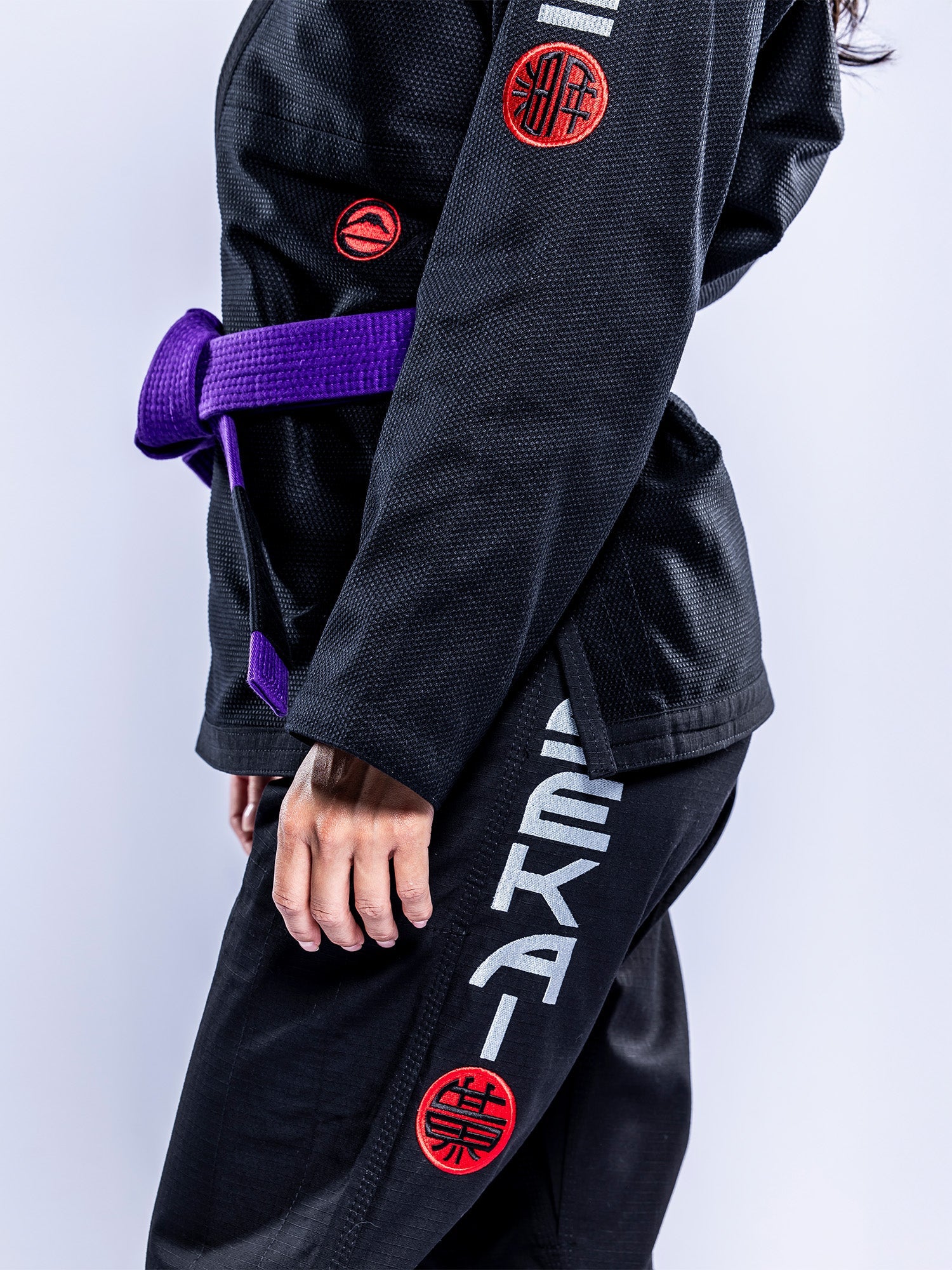 A person wears the Womens SEKAI 3.0 BJJ Gi Black Grey, standing against a plain background with their left arm, torso, and leg partially visible.